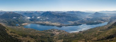 Alumine Gölü, açık bir gökyüzünün altındaki ormanlık tepelerin arasına kurulmuş. Los Andes, Patagonya, Arjantin 'in uzak sıradağları
