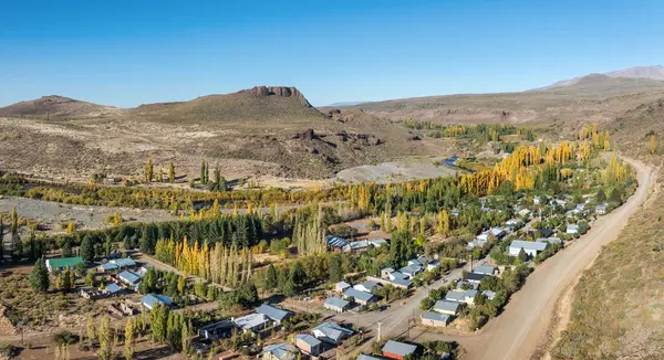 Villa del Nahueve köyünün hava manzarası, sonbahar yaprakları, dolambaçlı nehir ve berrak mavi gökyüzünün altındaki uzak tepelerin olduğu bir vadiye yerleşmiştir. Neuquen, Arjantin