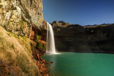 El Saltpo del Agrio şelalesi destansı renkli kaya oluşumlarıyla turkuaz su gölünde çağlıyor. Neuquen, Patagonya, Arjantin