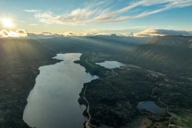 Güneş ışınları bulutları Norquinco Gölü ve Patagonya 'da dağlarla çevrili daha küçük su kütlelerini parçalı bulutlu bir gökyüzü altında deler. Neuquen, Arjantin