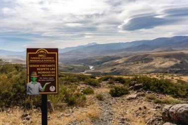Mirador La Puntilla 'nın kurak arazide yabancı bir figür ve gizemli bir bulut gösteren manzarası. 9 Nisan 2025 Neuquen, Arjantin