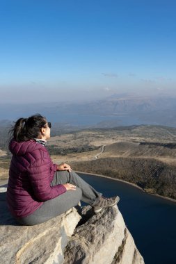 Kadın, Batea Mahuida, Villa Pehuenia, Neuquen, Arjantin 'deki panoramik göl ve çevre dağların keyfini çıkarıyor.