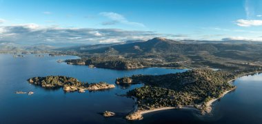 Bulutlu bir gökyüzünün altında dağlarla ve ormanlarla çevrili Alumine Gölü 'nün panoramik manzarası. Villa Pehuenia, Neuquen, Patagonya, Arjantin
