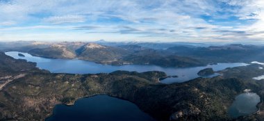 Alumine Gölü 'nün panoramik hava manzarası ve bulutlu Patagonya gökyüzünün altındaki daha küçük gölcükler. Karla kaplı tepeler uzaktan görülebilir. Villa Pehuenia, Neuquen, Arjantin
