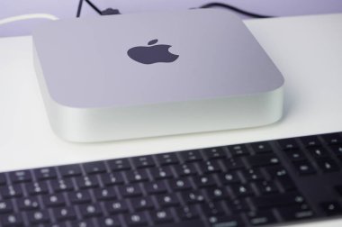 Mainz, Almanya - 26 Mart 2023: M1 çipli Apple Mac Mini beyaz bir masada kullanılıyor, önünde siyah bir elmalı klavye var