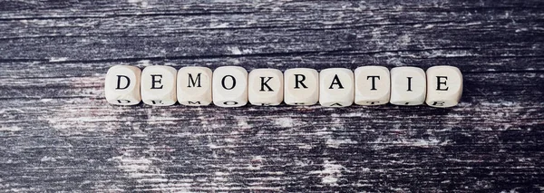 the german word for democracy laid from wooden cubes with letters on wooden background