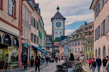 Freiburg, Almanya - Nisan 06, 2024: Almanya 'nın Freiburg im Breisgau kentindeki Martinstor' a doğru yürüyen insanlar