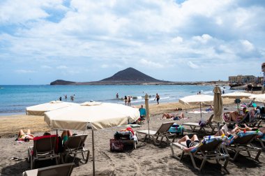 El Medano, Tenerife, İspanya - 22 Nisan 2024: Tenerife, İspanya 'nın sörf merkezi El Medano sahilindeki insanlar