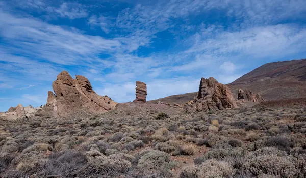 Teide Ulusal Parkı 'nın engin manzarasında parlak mavi gökyüzü altında eşsiz volkanik kaya oluşumları sergileniyor. Bu UNESCO sahasındaki doğanın güzelliğini vurguluyor..