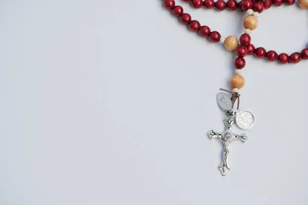 Güzelce işlenmiş bir tespih beyaz bir yüzeyde uzanır, duayı ve yansımayı davet eder..