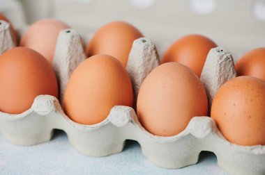 Taze kahverengi yumurtalar pürüzsüz kabuklarını ve doğal tonlarını sergileyerek bir kutunun içinde güzelce otururlar..