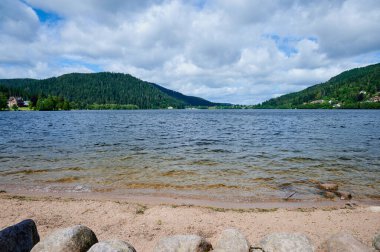 Gerardmer Gölü 'nün sakin suları bulutlu gökyüzünün altındaki dağları yansıtır. Rahatlamak için mükemmeldir..