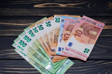 Tahta bir arka plana düzgünce yerleştirilmiş çeşitli avro banknotları, sergilenen para.