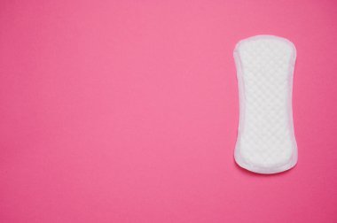 Tek bir kadın hijyen ürünü canlı pembe bir yüzeye yerleştirilmiştir. Bu görsel, regl sağlığı ve farkındalığın önemini vurgular..