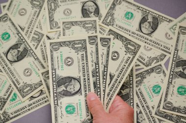 Diğerleri düz bir zemine saçılmışken bir el bir kaç dolarlık banknotları tutar.. 