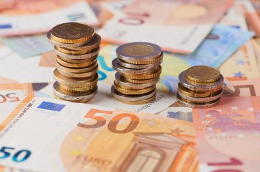 Bir masanın üzerindeki renkli avro banknotlarının yanına yığılmış madeni paralar zenginlik öneriyor..