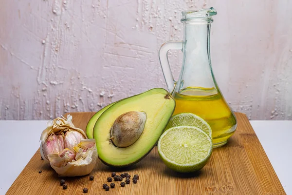Avokado macunu ürünleri. Avokado, limon, sarımsak, ahşap bir tahtada biber. Cam şeffaf bir şişede zeytin yağı. Parlak bir köy geçmişi var. İtalyan mutfağı. Restoran malzemeleri..