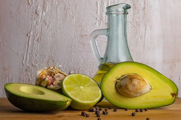 Avokado macunu ürünleri. Avokado, limon, sarımsak, ahşap bir tahtada biber. Cam şeffaf bir şişede zeytin yağı. Parlak bir köy geçmişi var. İtalyan mutfağı. Restoran malzemeleri..