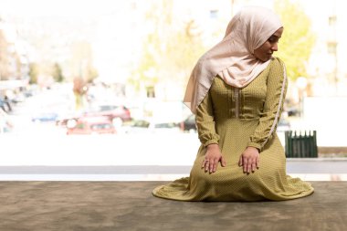 Camide oturmuş dua eden tesettürlü güzel Müslüman kadın.