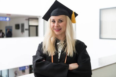 Happy Cute Blonde Caucasian Grad Girl is Smiling - She is in a Black Mortar Board clipart