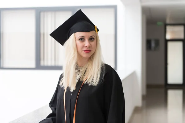 卒業時に自信を持って黒帽とガウンを身に着けている女性ブロンドの大学や高校卒業 — ストック写真