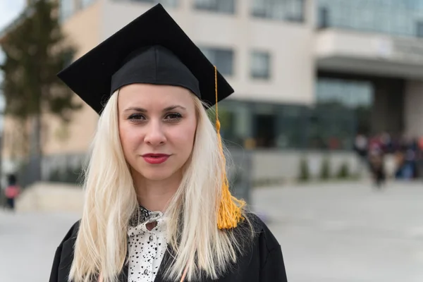 stock image Young Happy Woman University Graduates in Graduation Gown and Cap Holds a Degree Certificate to Celebrate Her Education Achievement on the Commencement Day