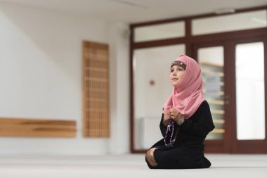 Geleneksel başörtüsü takmış, elinde tespih tutan Müslüman bir kızın portresi.