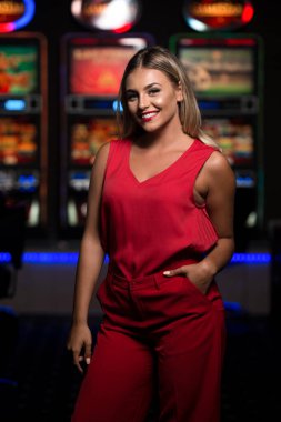 Güzel ve iyi giyimli, kırmızı elbiseli bir kızın portresi Kumarhanede oynuyor ve kutluyor.