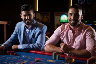 Kumarhanedeki rulet masasında geceleyin kumar oynayanlar.