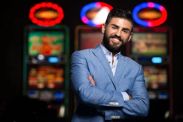 一个年轻貌美 衣冠楚楚的阿拉伯男子在赌场玩自动售货机 扑克牌或轮盘赌的肖像及庆典 — 图库照片