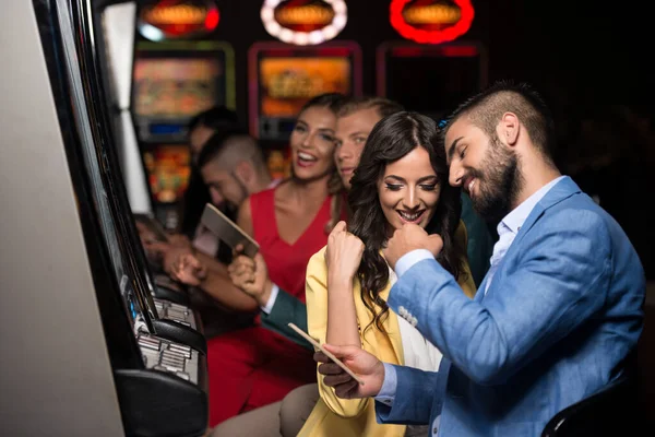 美しくよく服を着た友人がカジノで自動機械をプレイし — ストック写真