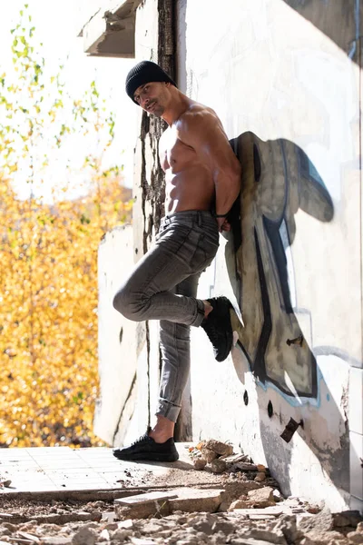 ハンサムな若い男が壁と曲げ筋肉に対してリーン 筋肉運動ボディビルダー男のポーズ — ストック写真