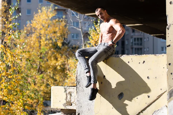 Hombre Joven Guapo Sentado Fuerte Aire Libre Músculos Flexionantes Ruinas —  Fotos de Stock