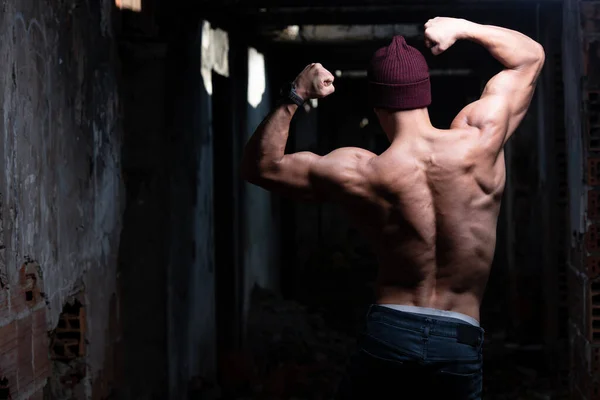 Здоровый Молодой Человек Зимней Шляпе Крепко Выпрямляя Мышцы Спины Руинах — стоковое фото