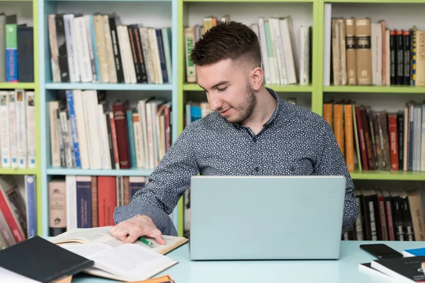 在图书馆里 一个英俊的男生 带着笔记本电脑和书本在高中工作 大学图书馆 — 图库照片