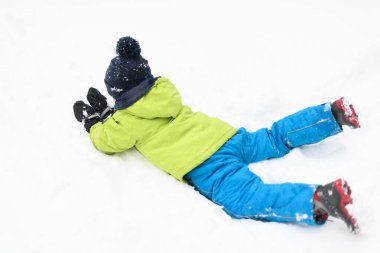 Kar yağışı sırasında küçük çocuk dışarıda karda oynuyor.