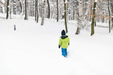 Küçük çocuk kar yağarken dışarıda eğleniyor ve karla oynuyor.