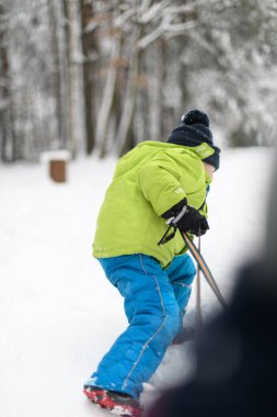 Kar yağışı sırasında dışarıda kızak çeken küçük çocuk.