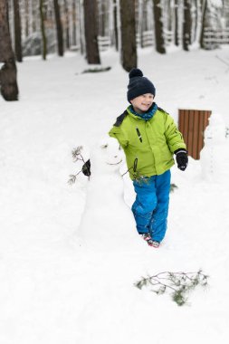 Küçük çocuk kar yağarken dışarıda eğleniyor ve karla oynuyor.