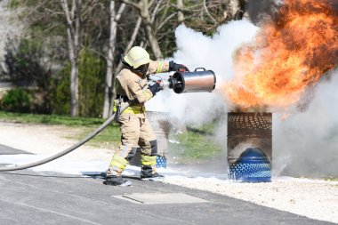 Sarı üniformalı itfaiyeci yağla savaşırken doğal ortamda köpükle ateş edebilir.