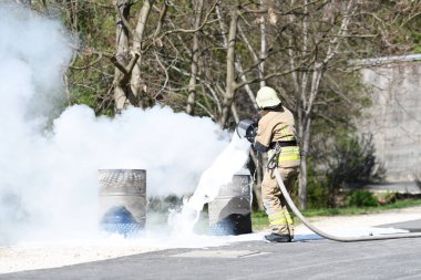 Sarı üniformalı itfaiyeci yağla savaşırken doğal ortamda köpükle ateş edebilir.