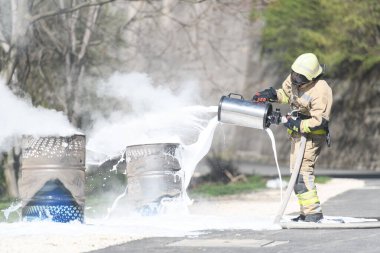 Sarı üniformalı itfaiyeci yağla savaşırken doğal ortamda köpükle ateş edebilir.