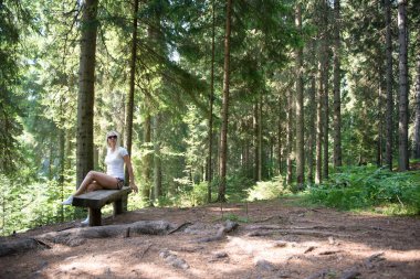 Ormandaki bir bankta poz veren kadın.