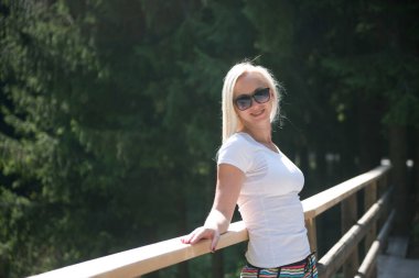 Etrafı ağaçlarla çevrili bir köprüye yaslanmış dinlendirici bir an