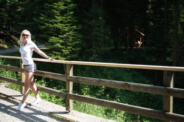 Etrafı ağaçlarla çevrili bir köprüye yaslanmış dinlendirici bir an