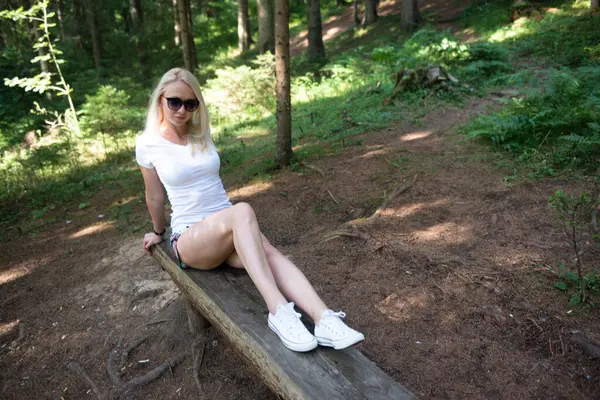 Ormandaki bir bankta poz veren kadın.