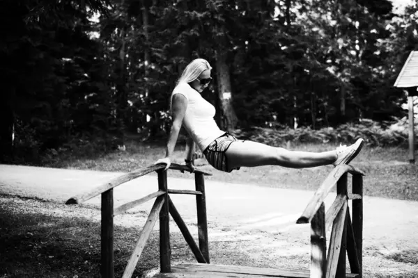 Ormanla çevrili bir köprüye yaslanan kadın