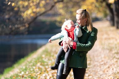 Güzel bir sonbahar ortamında bebeğini kucaklayan anneyi sevmek 