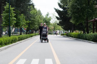 Bebek arabasıyla güneşli bir gezintinin tadını çıkaran iki kadın