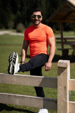 Güneşli bir günde, manzaralı bir yerde ısınmaya çalışan adam.